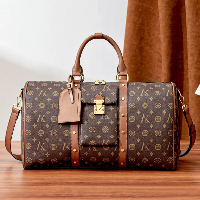 Sac de voyage marron à motif monogramme, anses supérieures, bandoulière réglable, poche avant et dét